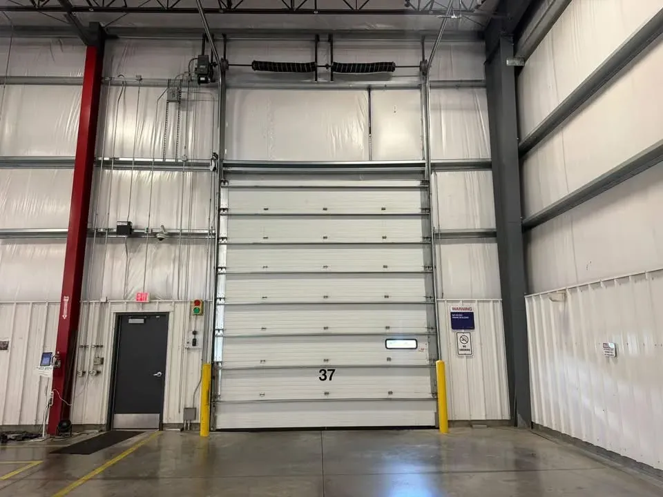 An insulated commercial sectional door, closed, in a metal building