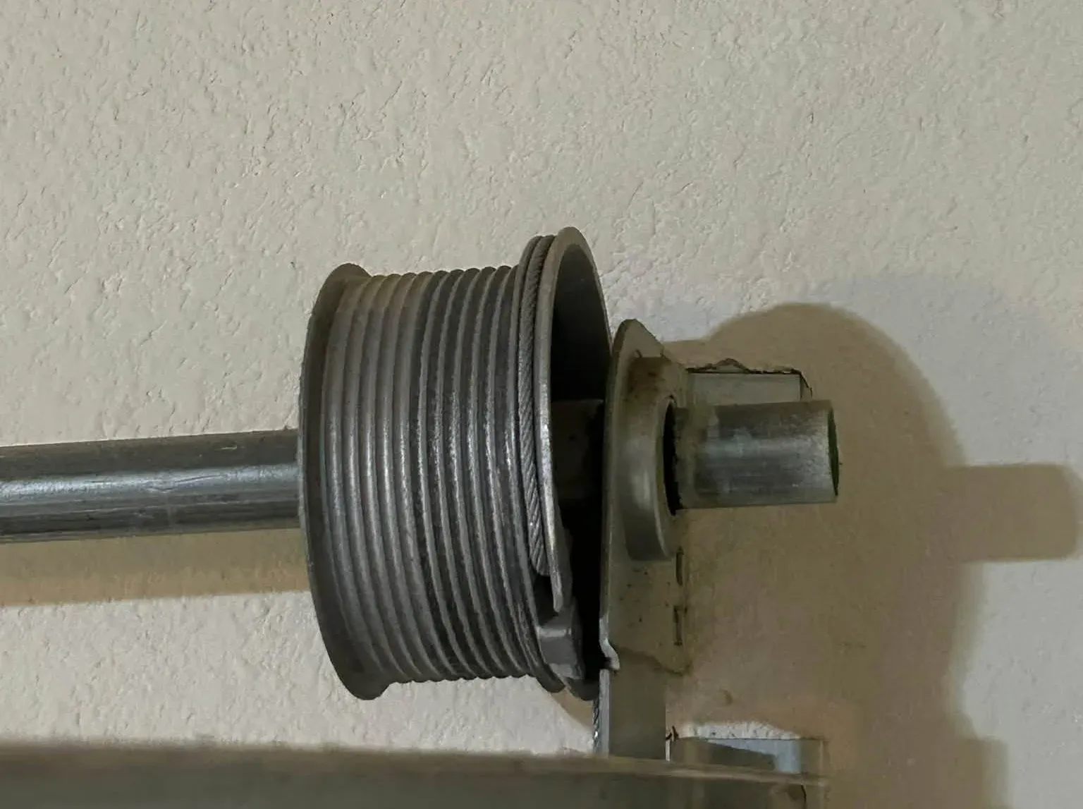 A cable drum on the spring shaft, the lift cable seated in its grooves