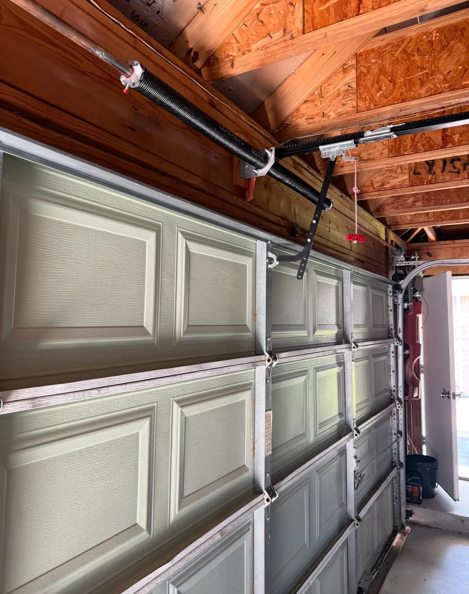 A garage door from inside with a new torsion spring on its shaft