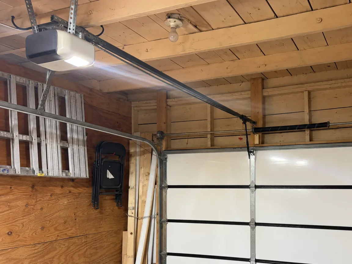 A garage door opener hanging from the ceiling, its rail running to the door
