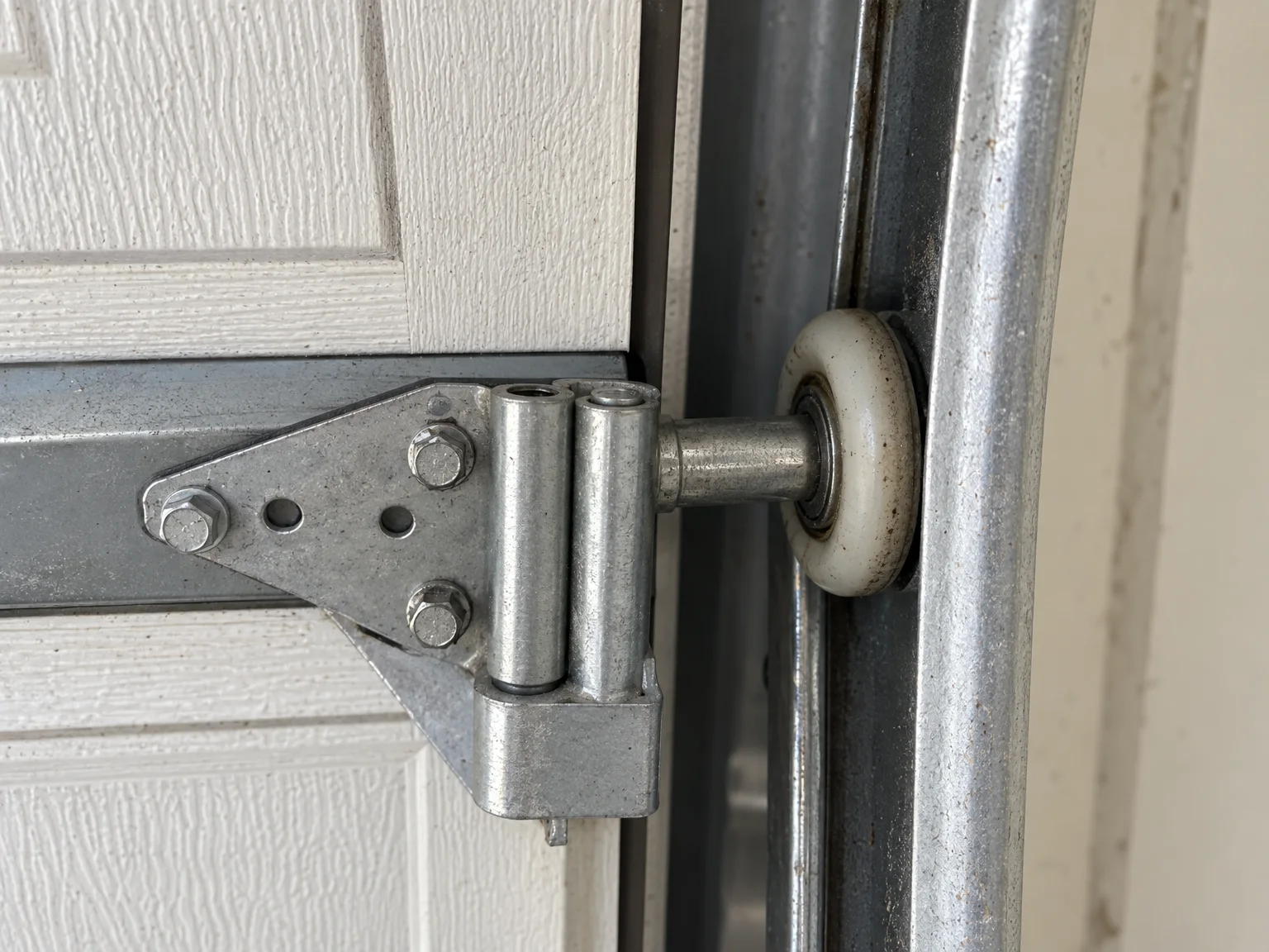 A nylon roller running in a steel garage door track
