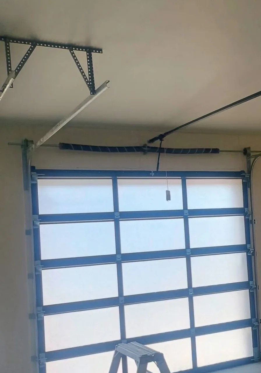 A garage mid-job, a full-view glass door and two ladders