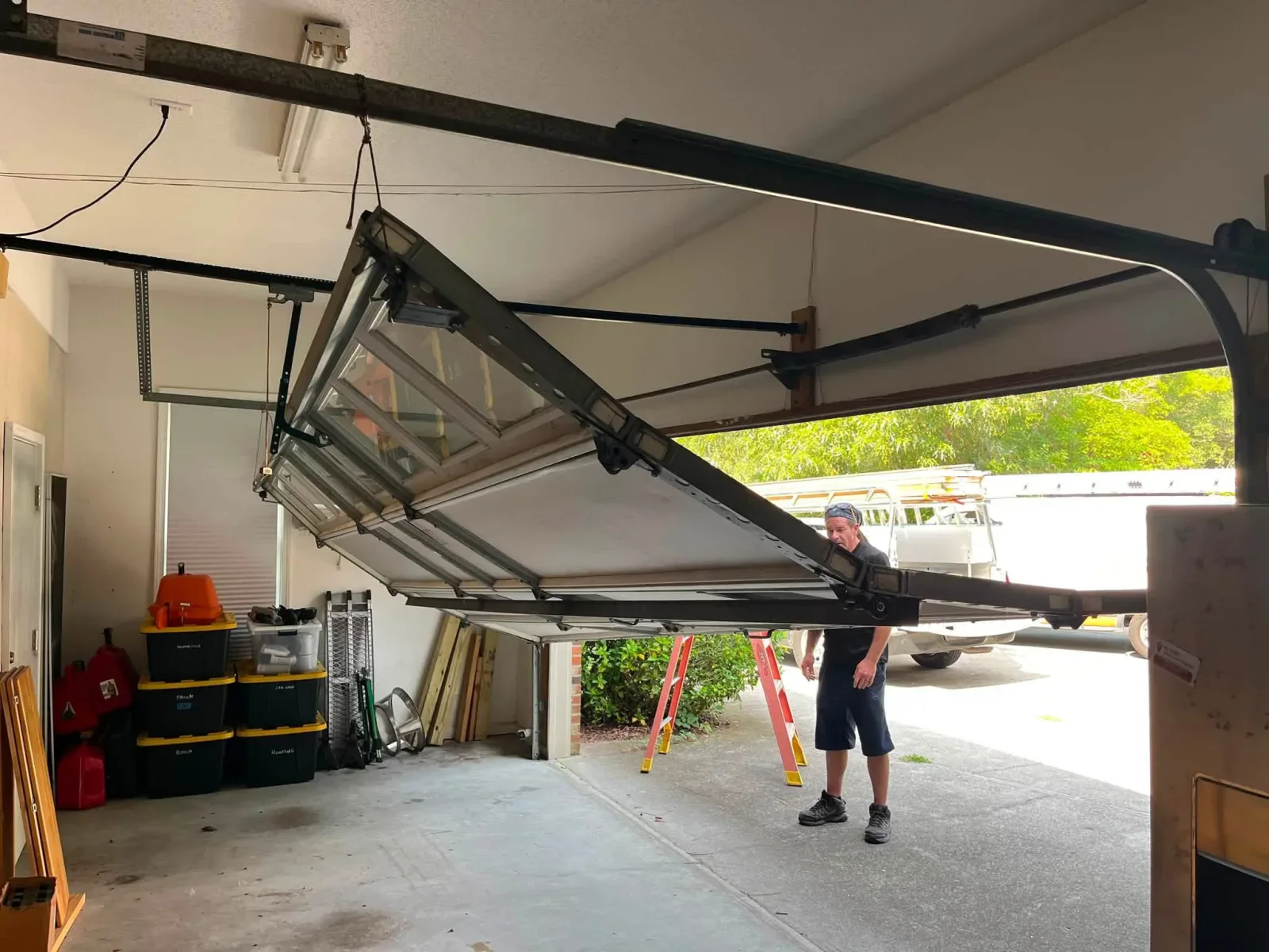 A technician checking a full-view garage door hanging off its track