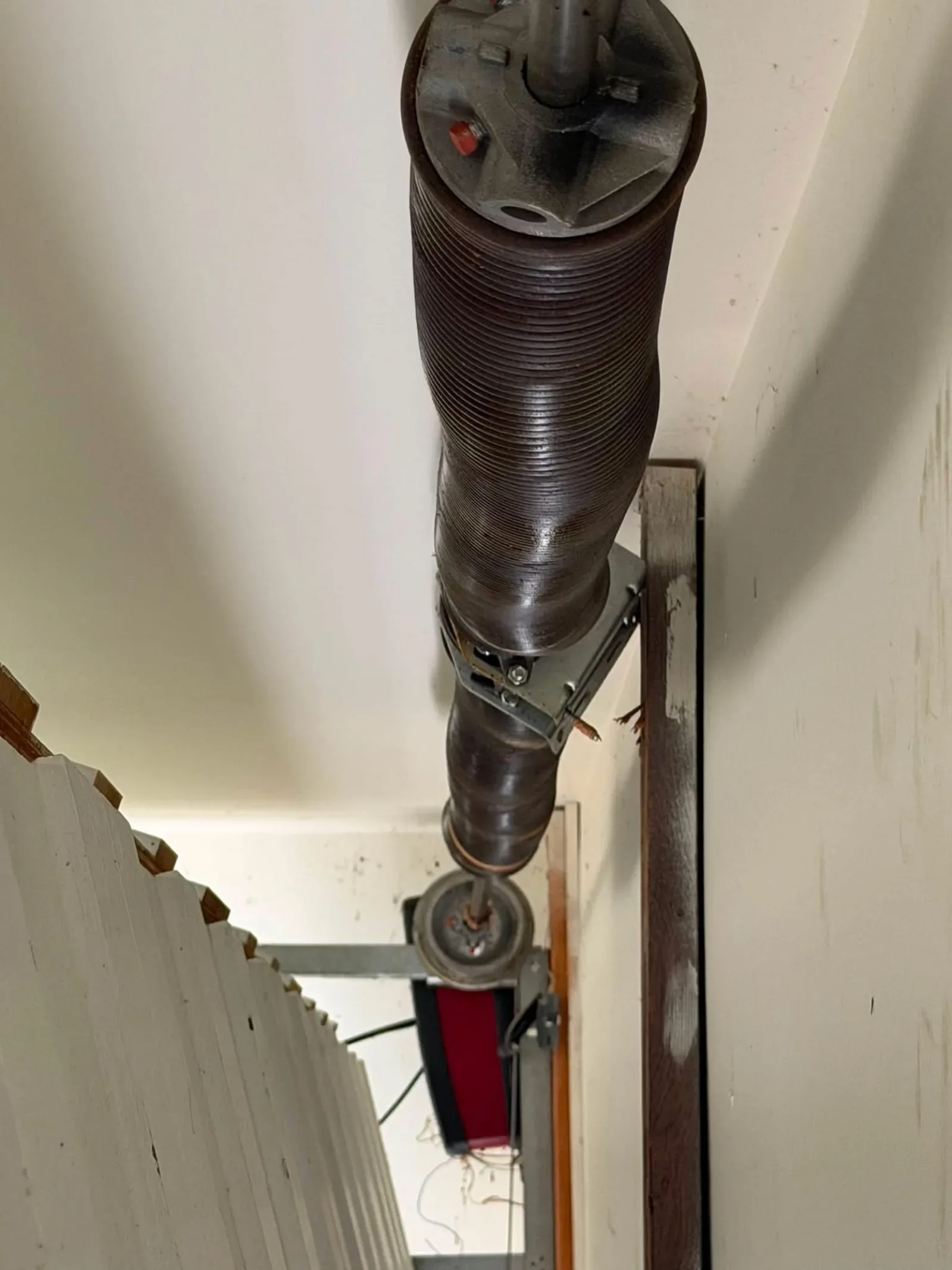A torsion spring on its shaft above a garage door, seen from below