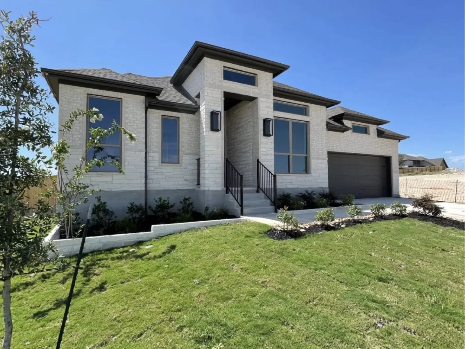 A stone house on a rise with a dark garage door