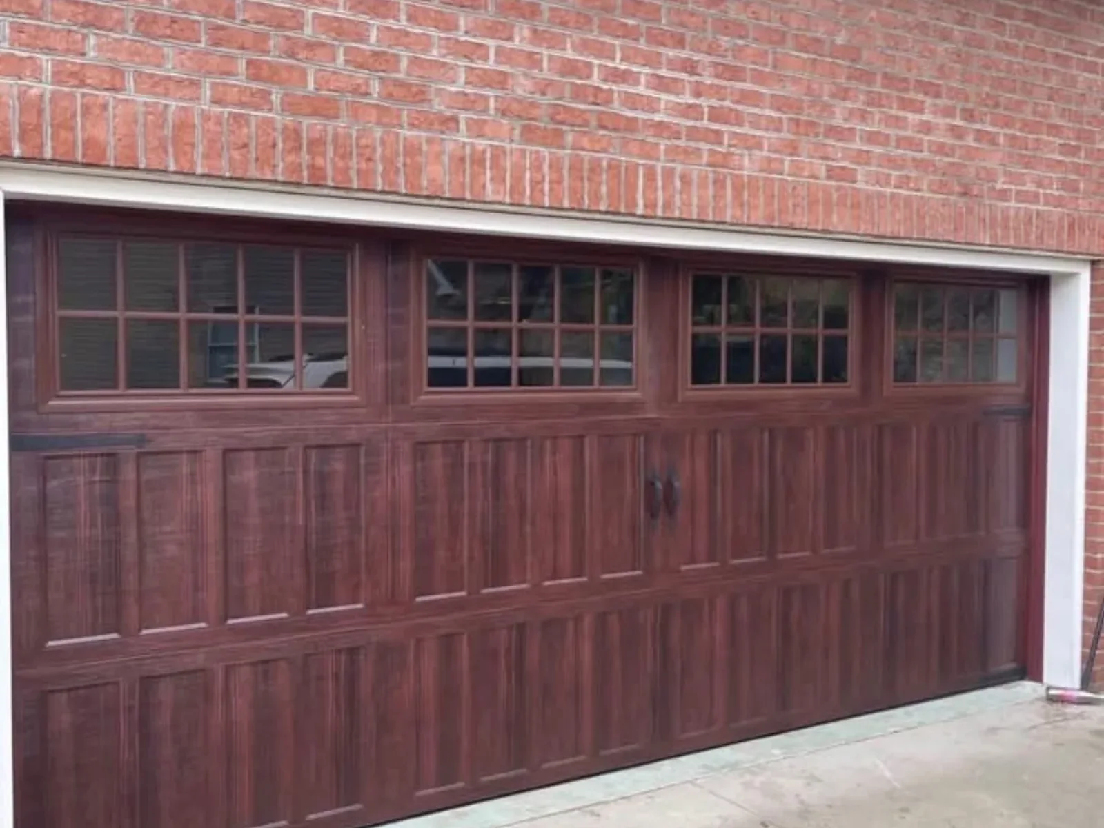 A walnut wood-look carriage garage door on brick