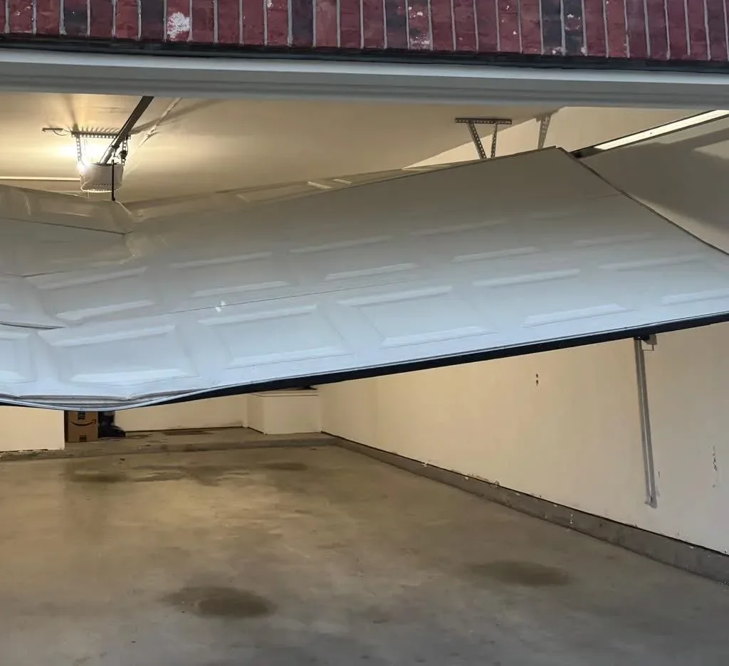 A buckled garage door section inside a garage