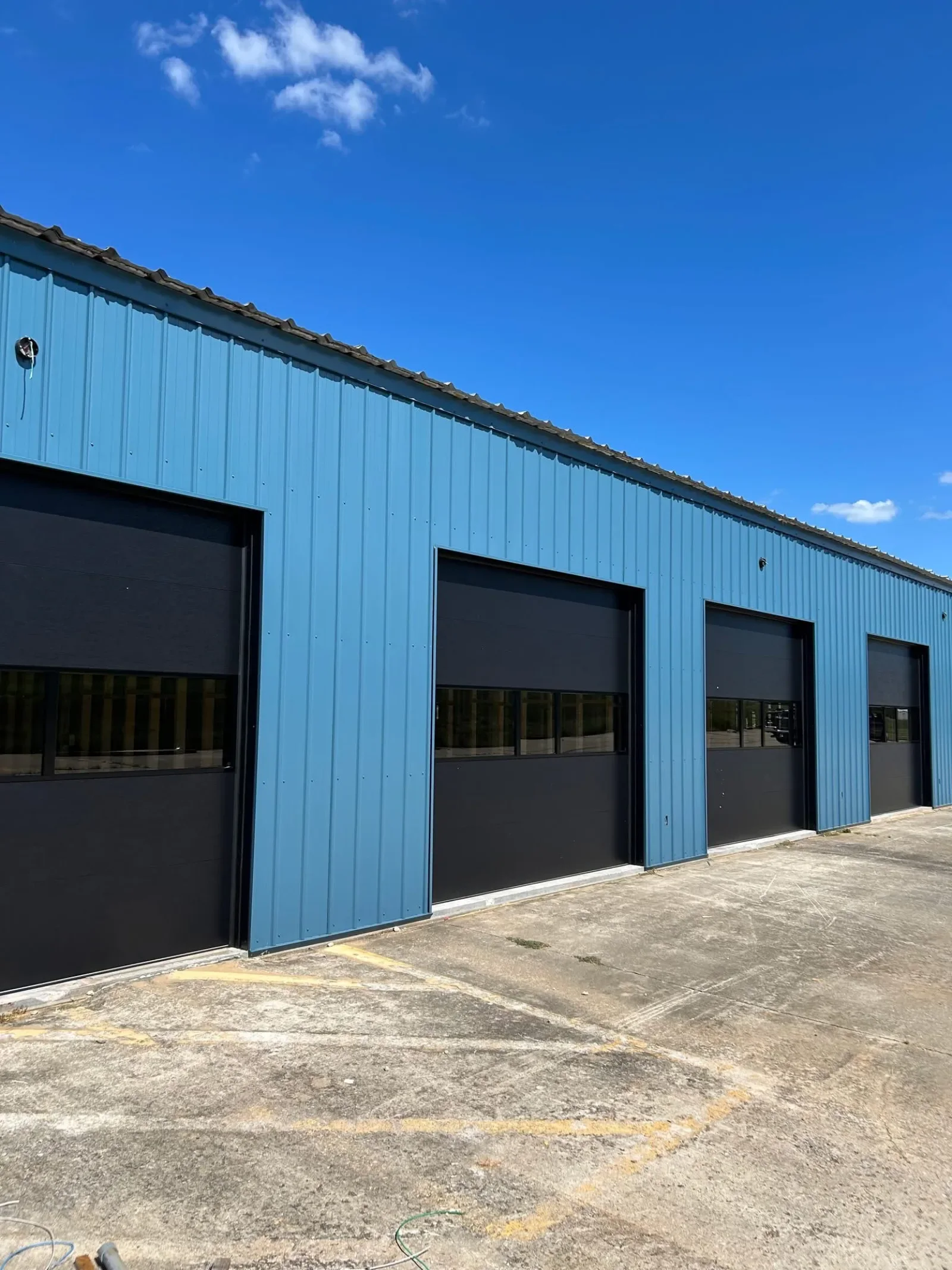 A row of commercial doors on a blue metal building