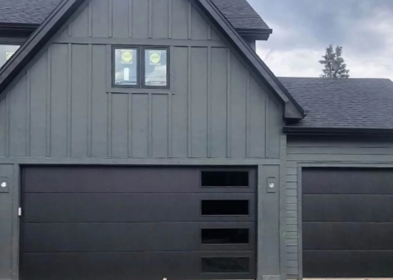 Black flush garage doors on a board-and-batten house