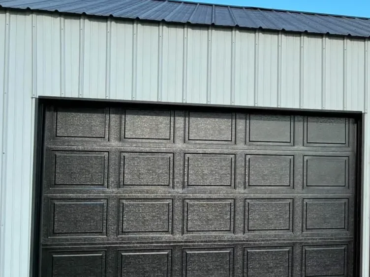 A black sectional door on a metal building