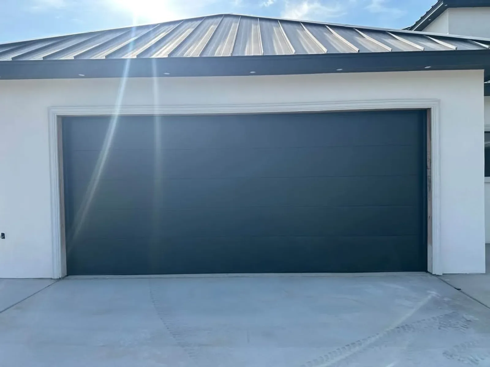A flush dark garage door on white stucco