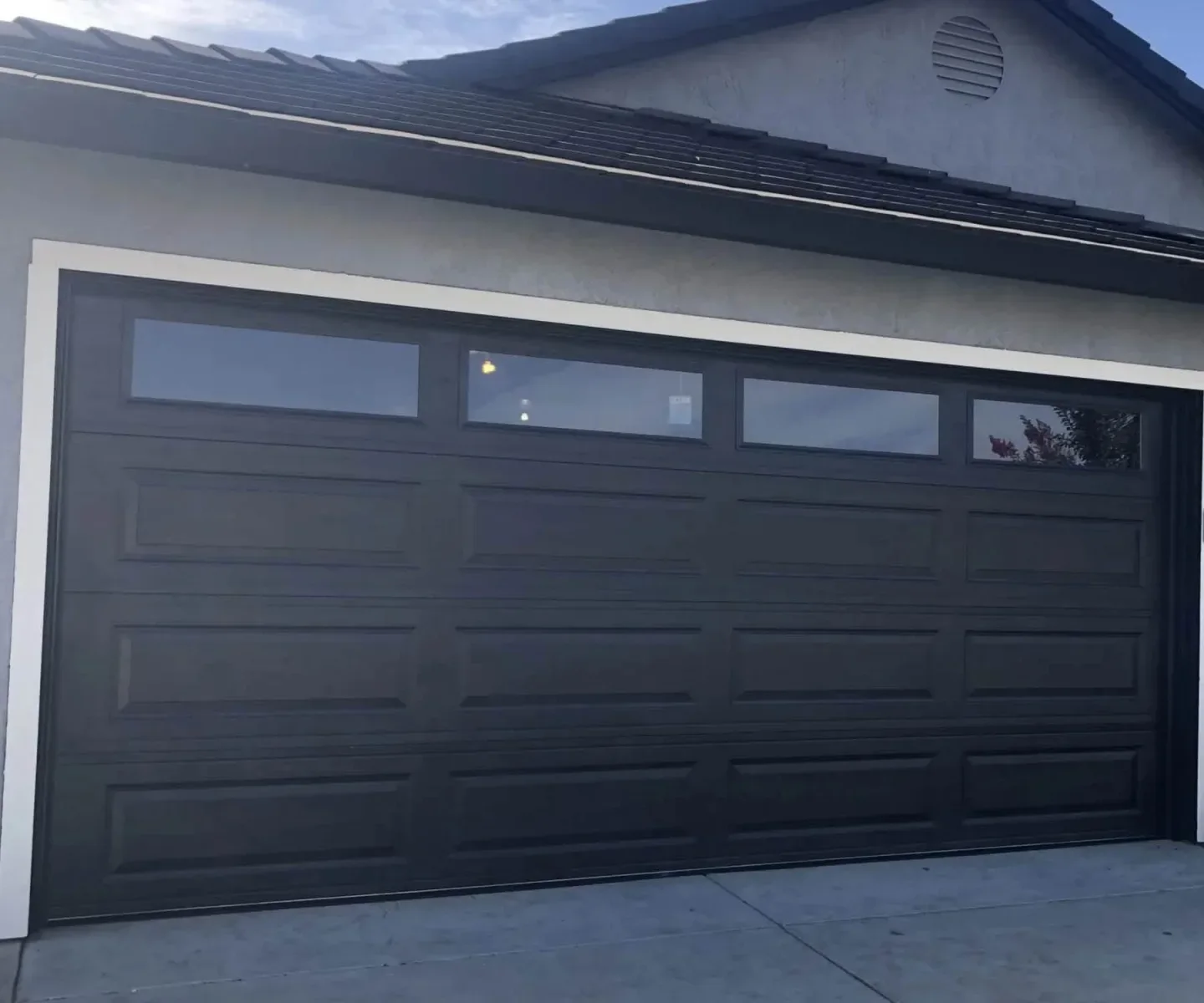 A dark long-panel garage door with a row of windows