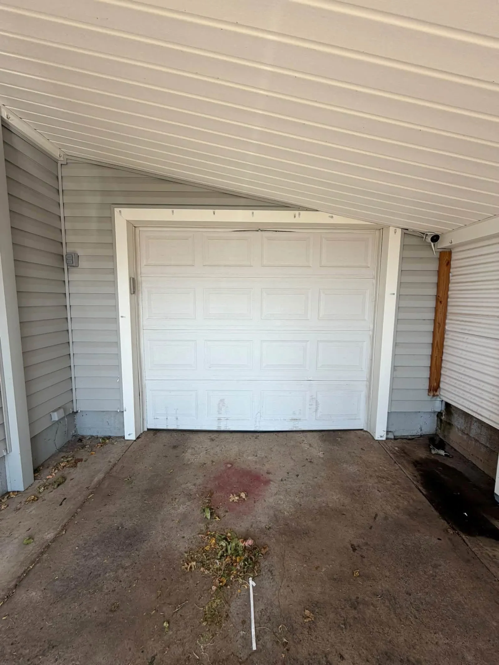 Before: an old white garage door under a carport