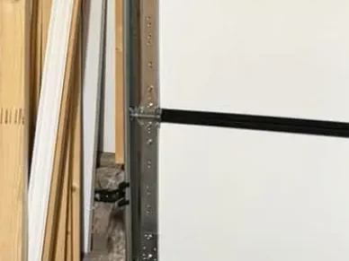 A photo-eye sensor on its bracket at the foot of a garage door track