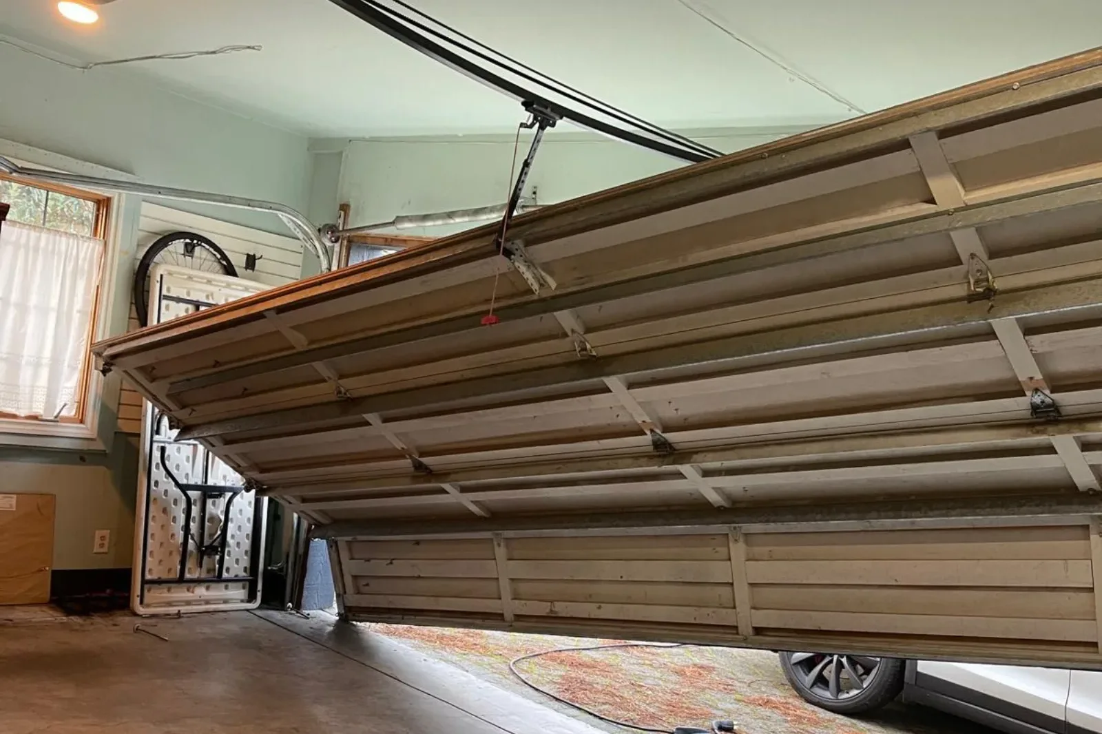 A garage door hanging off its track inside a garage
