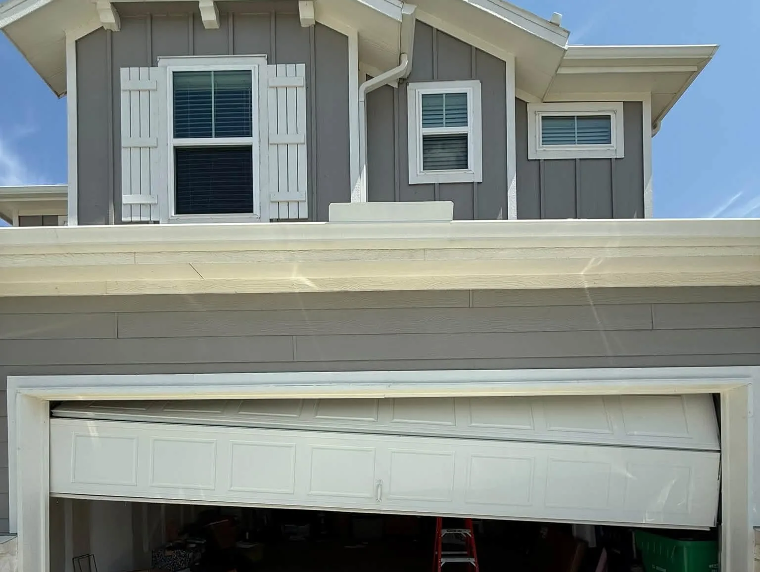A garage door hanging crooked in its opening