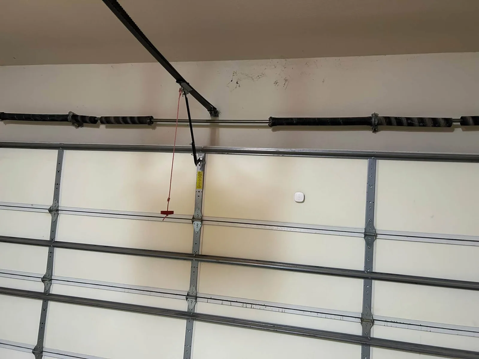 A closed garage door from inside, its springs above it