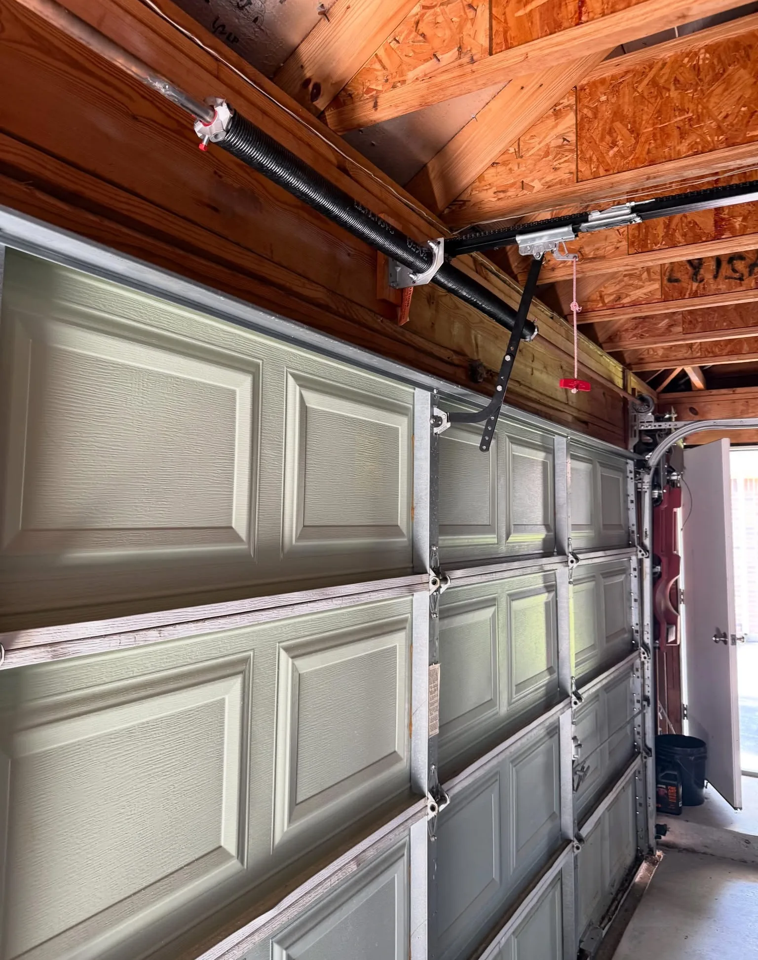 A garage door from inside with a new torsion spring on its shaft