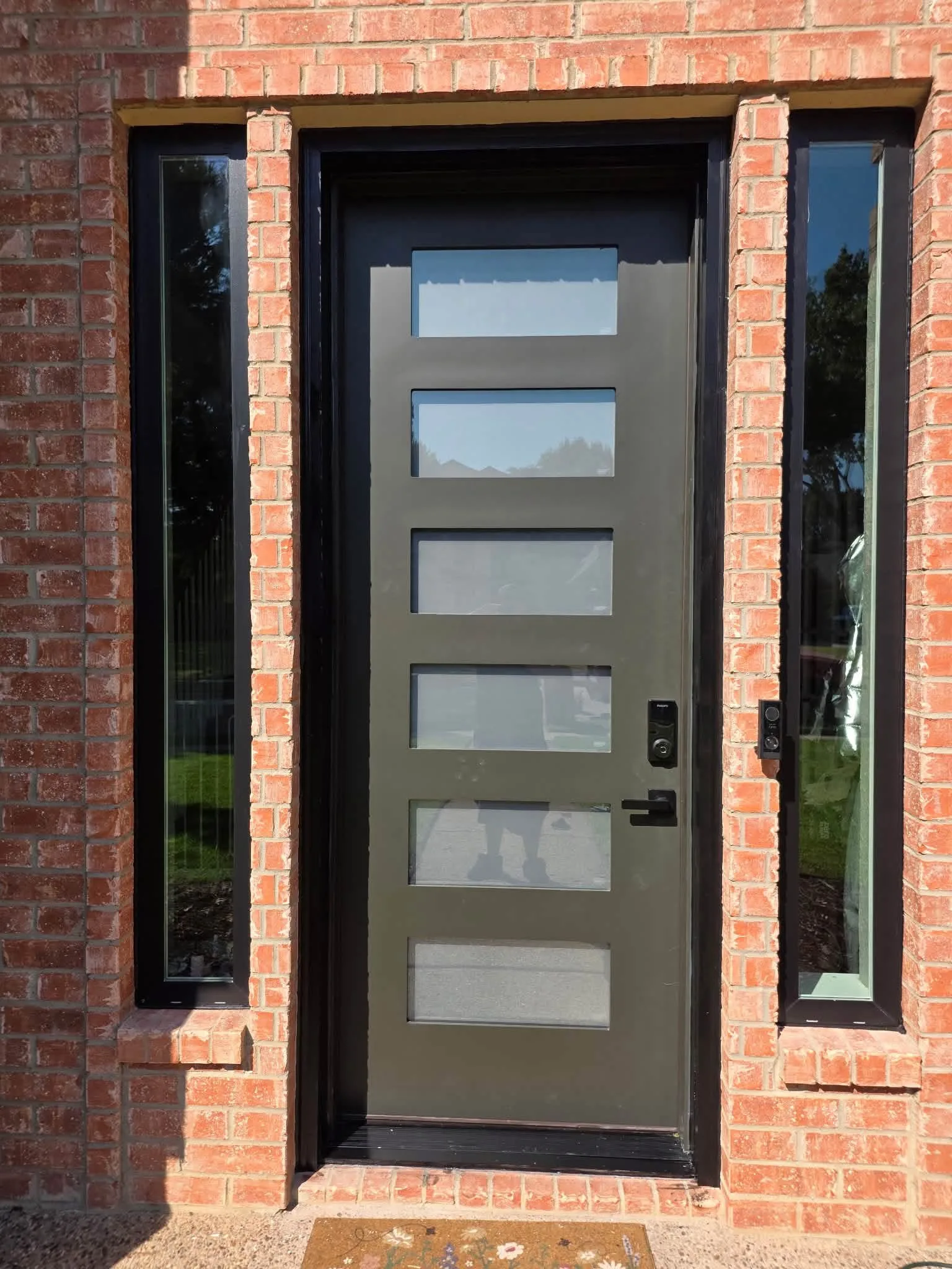 A modern entry door with sidelights in red brick