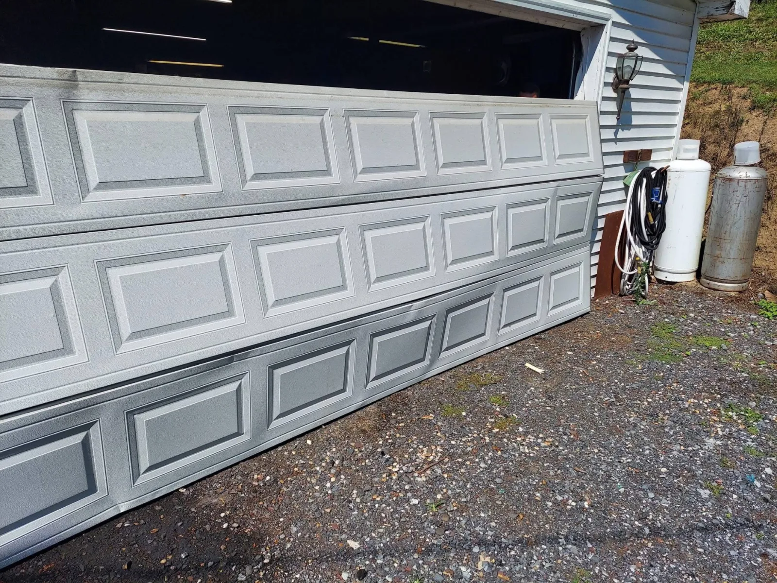 A buckled garage door leaning out of its opening